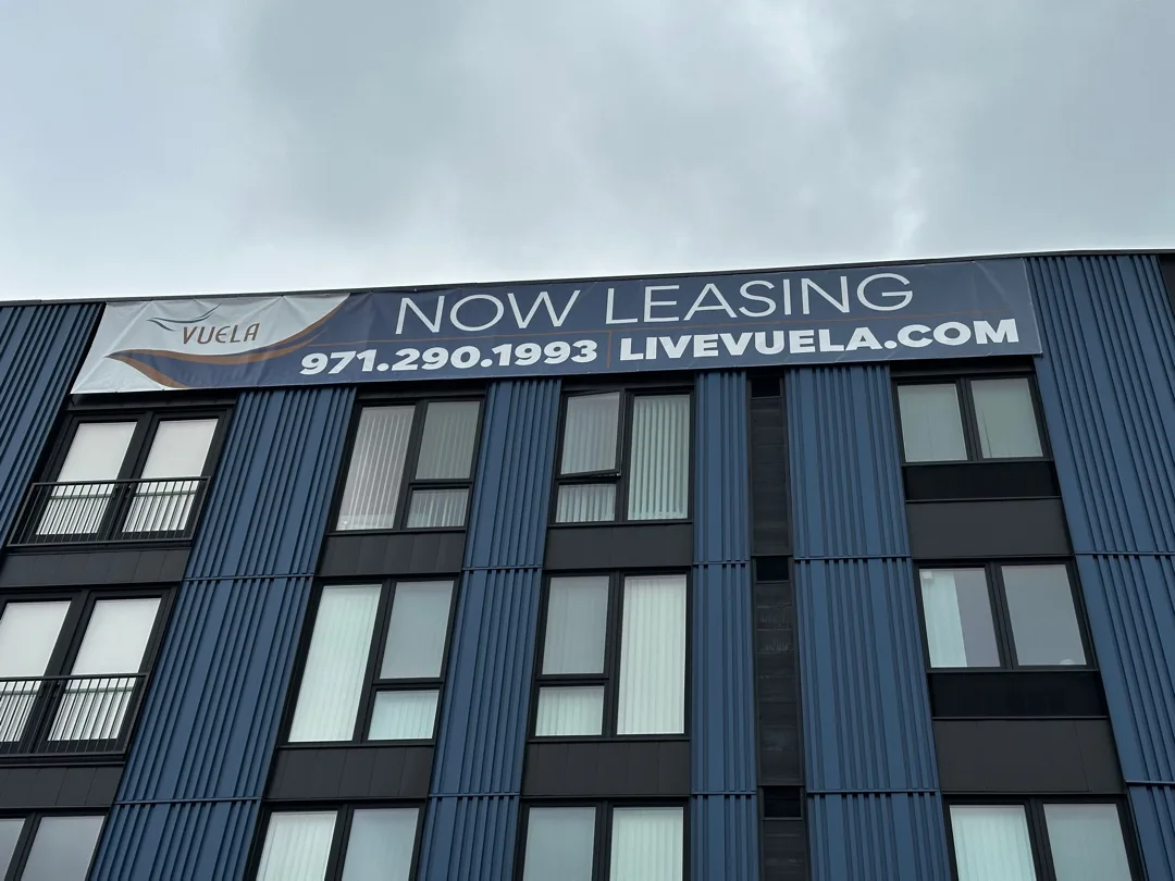 Completed 40-foot Vuela leasing banner secured across the apartment building