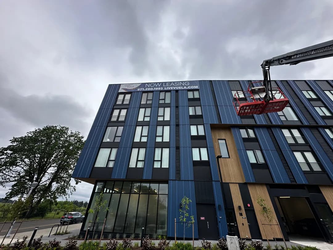 AP crew installing a multi-story exterior banner at the Vuela apartment building