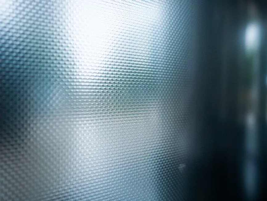 Close-up of textured glass panel with light reflection