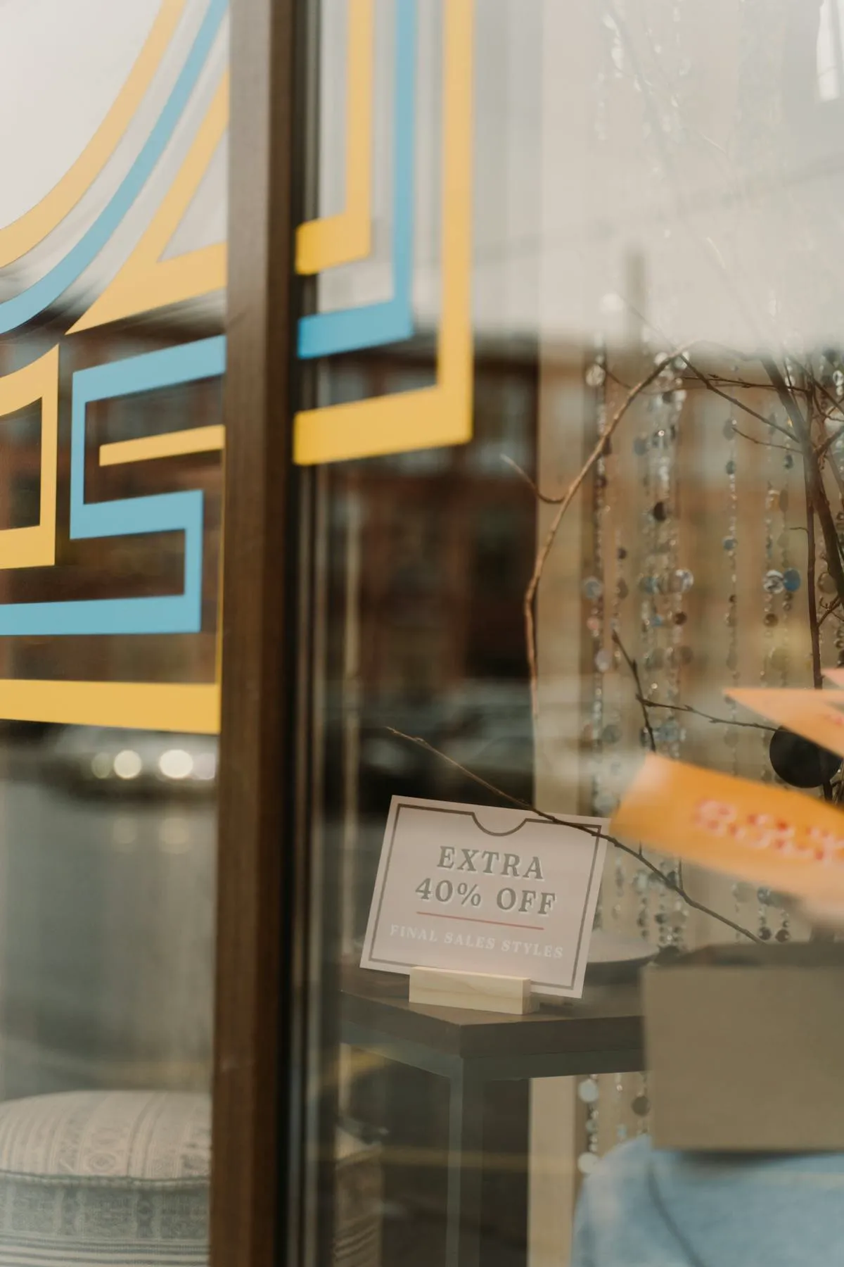 Glass storefront window with promotional sale signage displayed inside